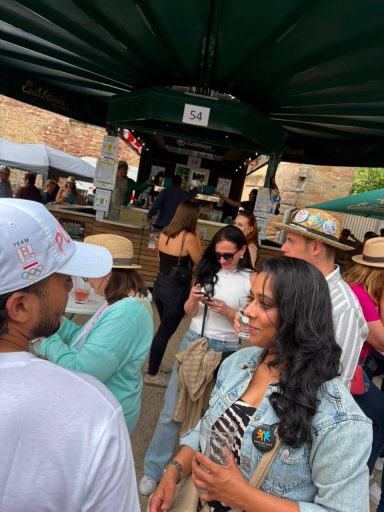 Menschen auf einem Markt, darunter eine Frau mit langen, lockigen Haaren und anderen Besuchern.