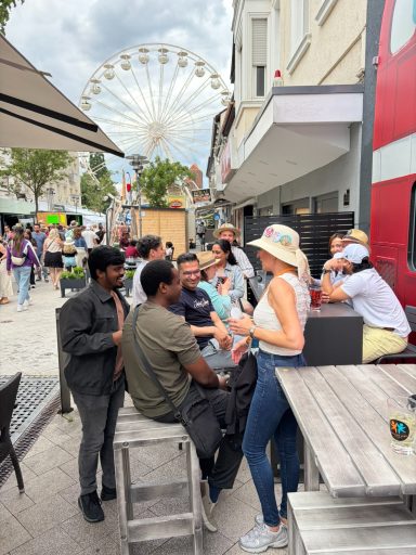 Die Gruppe von Menschen unterhält sich fröhlich vor einem Riesenrad.