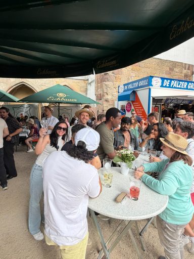 Menschen genießen Getränke und essen an einem Außenstand auf einem Fest.