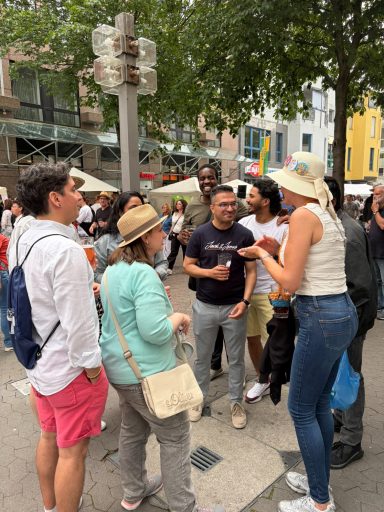 Gruppe von Menschen bei einem Straßenfest, einige trinken und lachen.