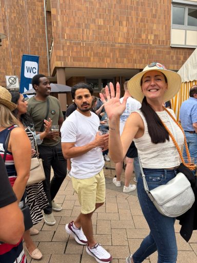 Menschenmenge auf der Straße, eine Frau winkt begeistert, kurzer Blick auf ihre Umgebung.