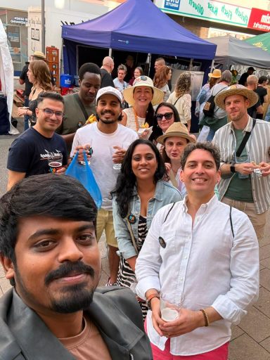 Gruppe von neun Personen lächelt und posiert fröhlich auf einem Sommerfest.